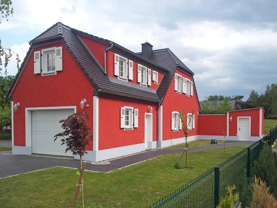 Neubau im Landhausstil mit roter Fassade und Garage